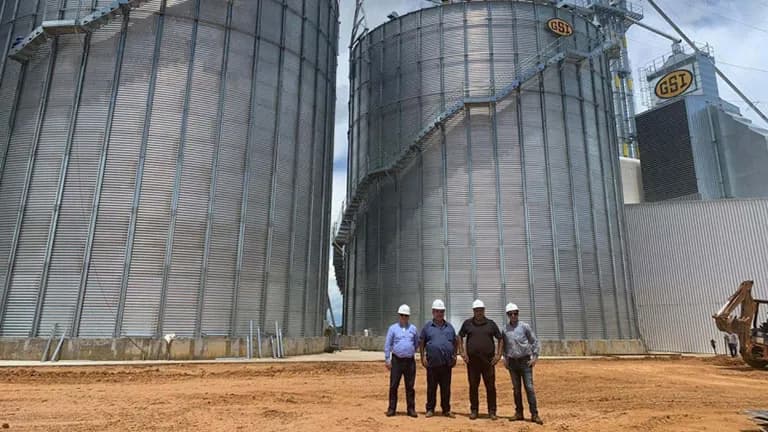 Equipe com capacetes na frente de silos GSI em construção