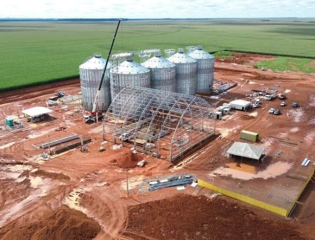 Vista aérea de construção de complexo graneleiro com silos e armazém